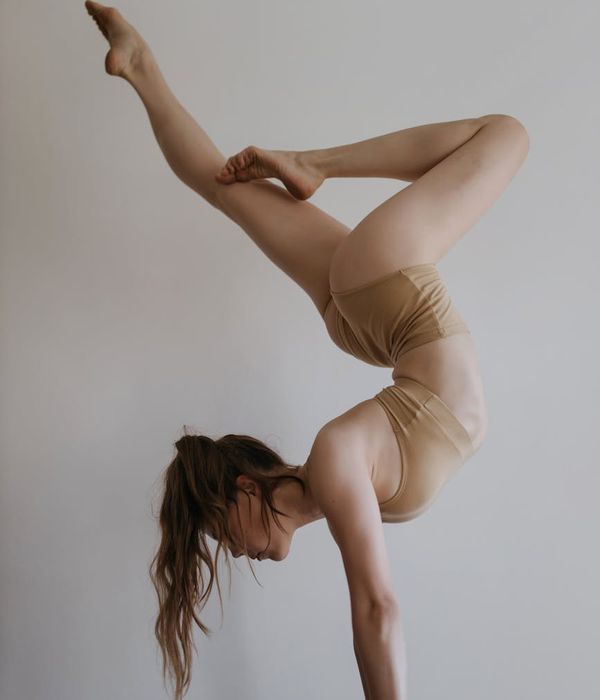 Woman maintaining a difficult balancing yoga pose in a calm studio.